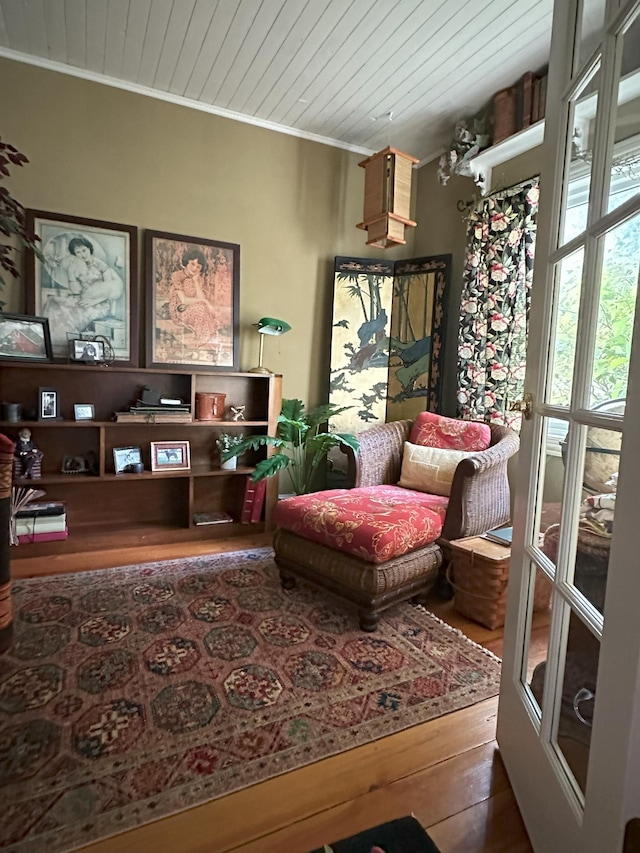 living area featuring ornamental molding, hardwood / wood-style floors, and wooden ceiling