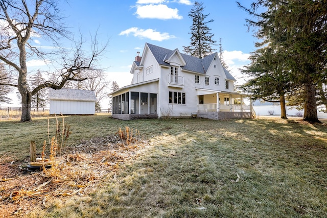 exterior space featuring an outbuilding, a lawn, and a sunroom