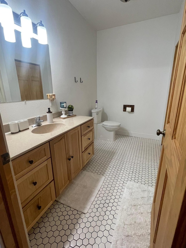 bathroom with toilet, vanity, and tile patterned flooring