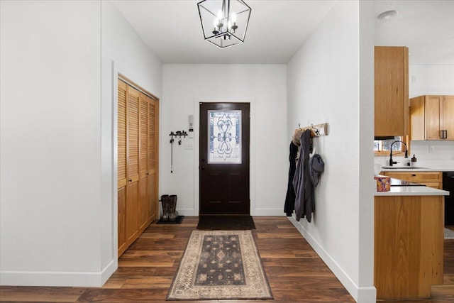 entryway featuring dark wood-type flooring, sink, and a chandelier