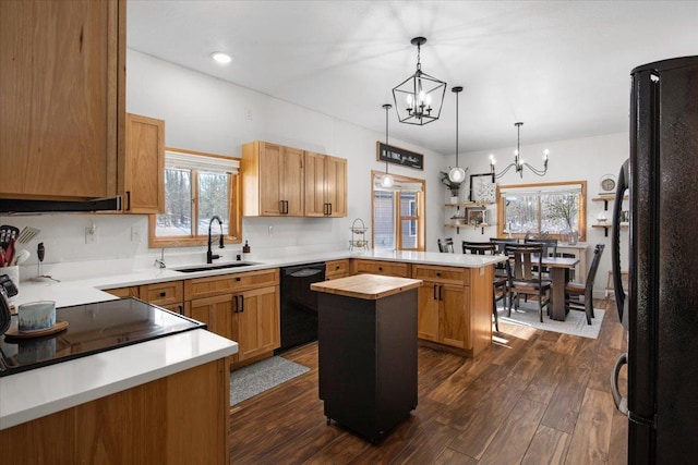 kitchen with pendant lighting, black appliances, a center island, kitchen peninsula, and sink