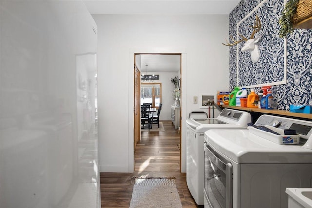 clothes washing area with washer and dryer, dark hardwood / wood-style flooring, and a notable chandelier