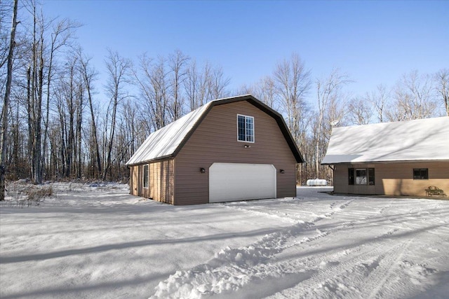 view of snowy exterior with an outdoor structure and a garage