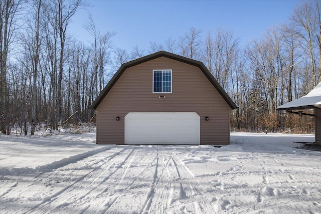 snow covered property featuring a garage and an outbuilding