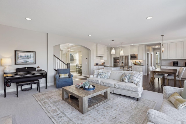 living room with arched walkways, recessed lighting, baseboards, and stairs