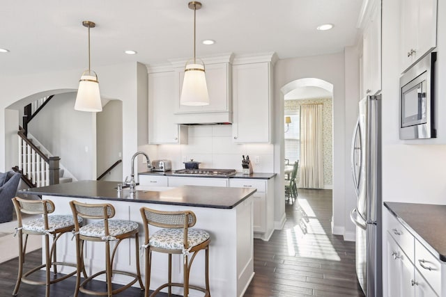 kitchen featuring dark countertops, white cabinetry, stainless steel appliances, and hanging light fixtures