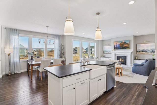 kitchen with decorative light fixtures, dark countertops, open floor plan, white cabinetry, and a sink