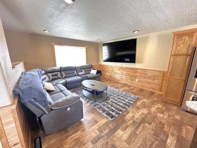 living room with a textured ceiling, wood walls, and dark hardwood / wood-style floors