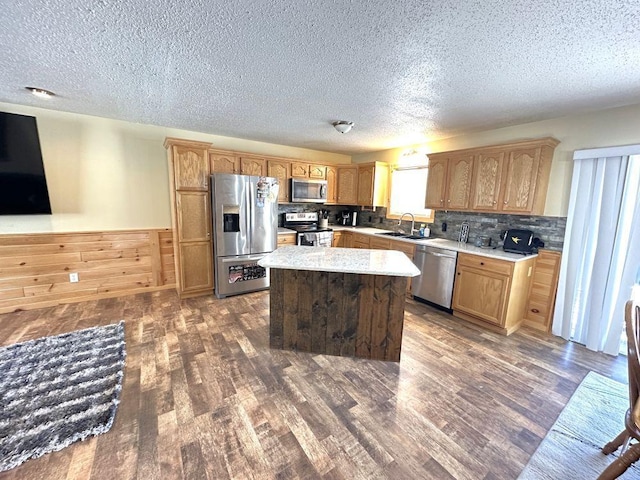 kitchen with appliances with stainless steel finishes, tasteful backsplash, sink, dark hardwood / wood-style floors, and a kitchen island