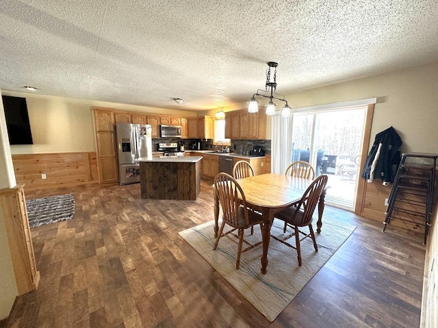 dining space featuring wood walls, dark hardwood / wood-style flooring, a textured ceiling, and sink