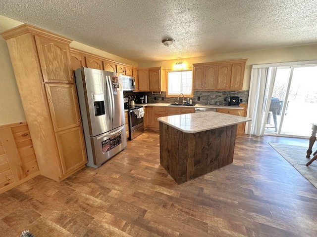 kitchen featuring a center island, backsplash, sink, a textured ceiling, and appliances with stainless steel finishes