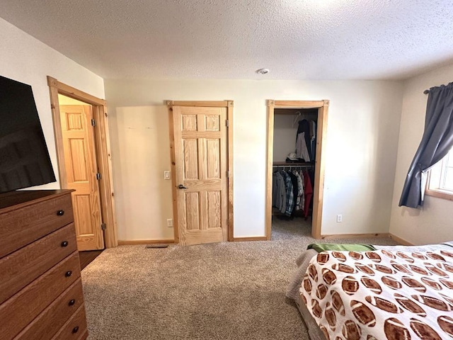 bedroom featuring carpet flooring, a walk in closet, a closet, and a textured ceiling