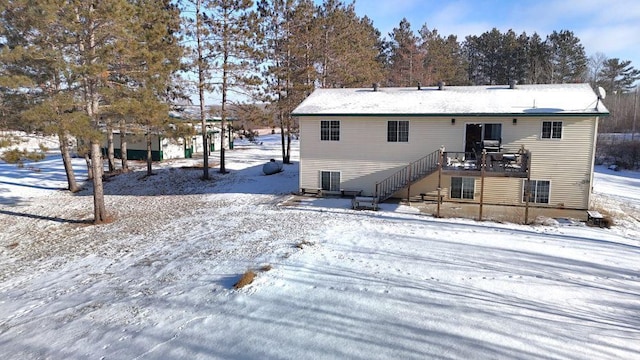 snow covered rear of property with stairway