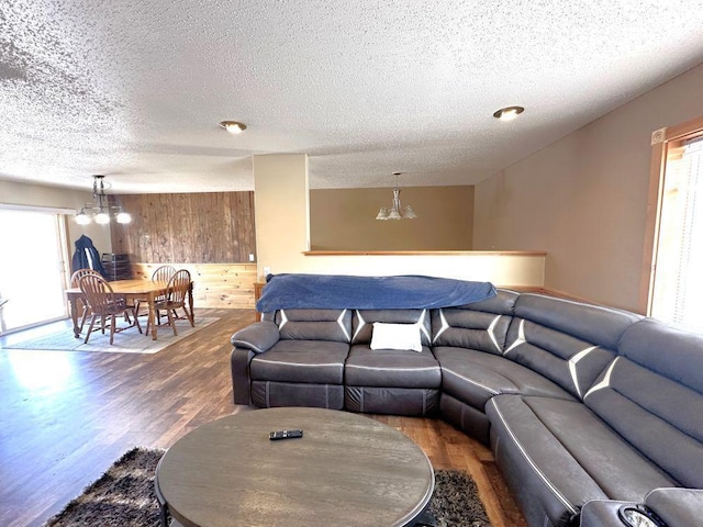 living area with wooden walls, wood finished floors, and an inviting chandelier