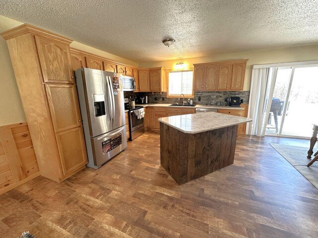 kitchen featuring light countertops, dark wood-type flooring, a kitchen island, a sink, and appliances with stainless steel finishes