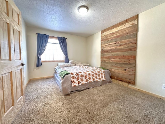bedroom featuring baseboards, carpet flooring, a textured ceiling, and wood walls