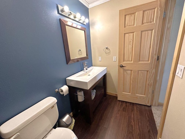 bathroom with toilet, crown molding, baseboards, and wood finished floors