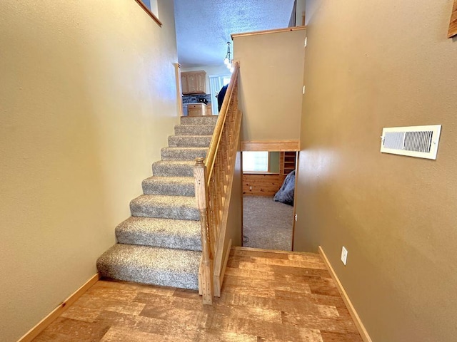 staircase featuring baseboards and visible vents