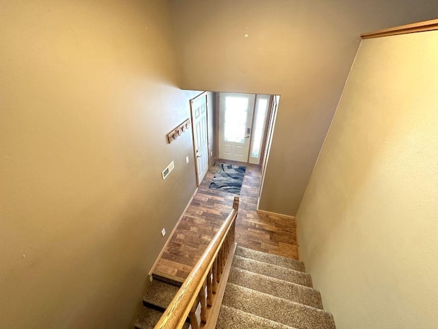 stairway featuring wood finished floors and visible vents