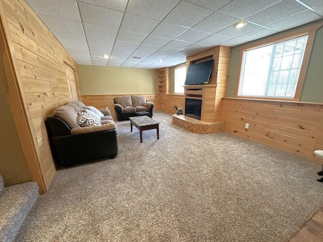 living room with carpet flooring, a wainscoted wall, a glass covered fireplace, and wooden walls