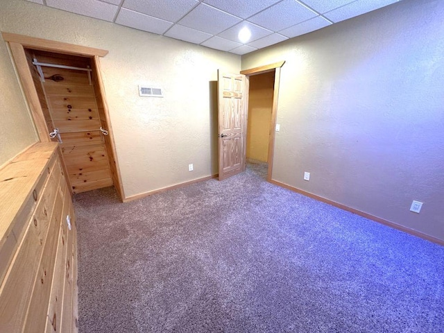 unfurnished bedroom with baseboards, carpet floors, visible vents, and a drop ceiling