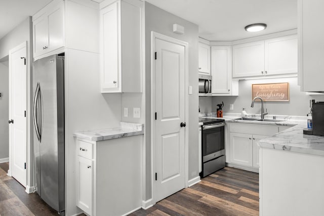 kitchen with sink, stainless steel appliances, white cabinets, dark hardwood / wood-style flooring, and light stone counters