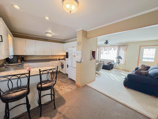 kitchen with white cabinets, sink, ceiling fan, white fridge, and carpet floors