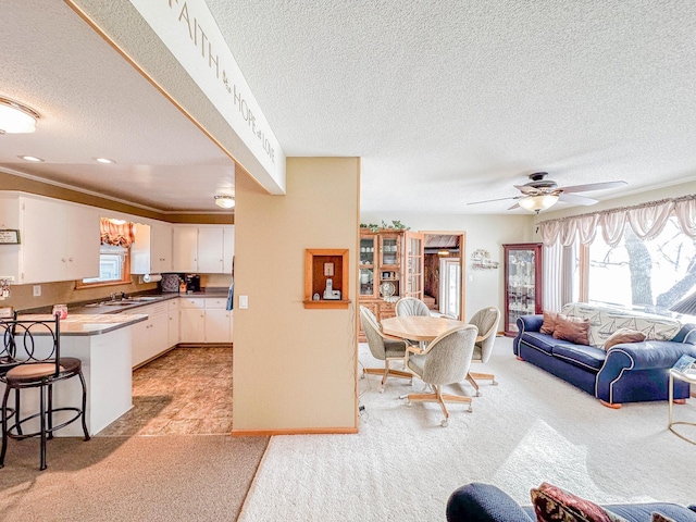 interior space featuring ceiling fan, light colored carpet, white cabinetry, and sink