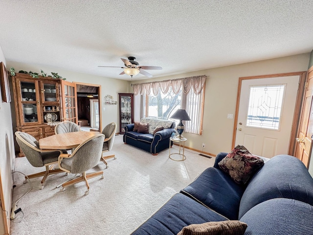 carpeted living room featuring ceiling fan and a textured ceiling