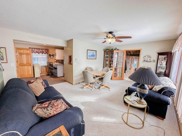 carpeted living room featuring ceiling fan and a textured ceiling