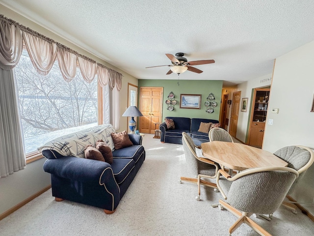 carpeted living room with a wealth of natural light, ceiling fan, and a textured ceiling