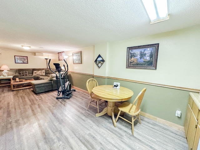 dining room featuring a wall mounted air conditioner, light hardwood / wood-style floors, and a textured ceiling