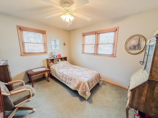 bedroom with multiple windows, ceiling fan, carpet flooring, and baseboards