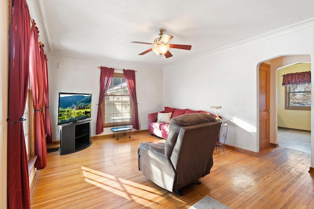 living room with ceiling fan, crown molding, and light wood-type flooring