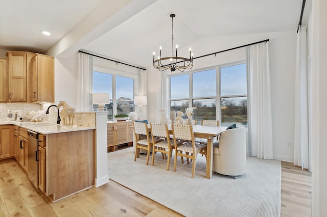 dining room with light hardwood / wood-style floors, sink, lofted ceiling, and a chandelier