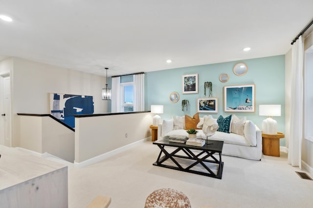 carpeted living room with a chandelier