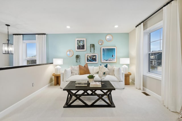 living room with light colored carpet and a notable chandelier