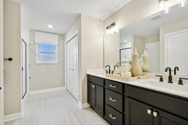 bathroom featuring a shower with shower door and vanity