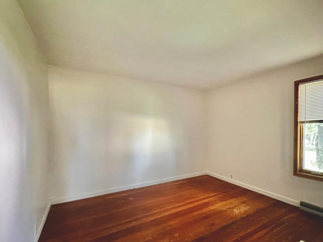 spare room featuring a baseboard radiator and dark hardwood / wood-style floors