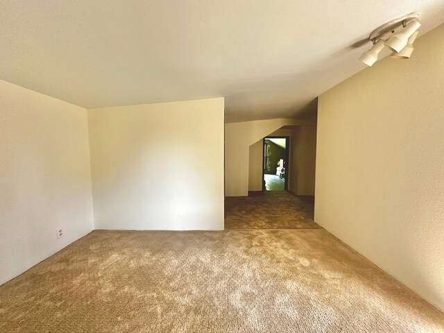 carpeted spare room with lofted ceiling