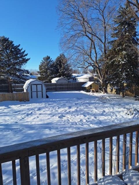 yard layered in snow featuring a shed