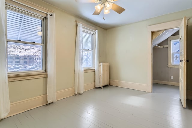 unfurnished room featuring ceiling fan, radiator, and light hardwood / wood-style flooring