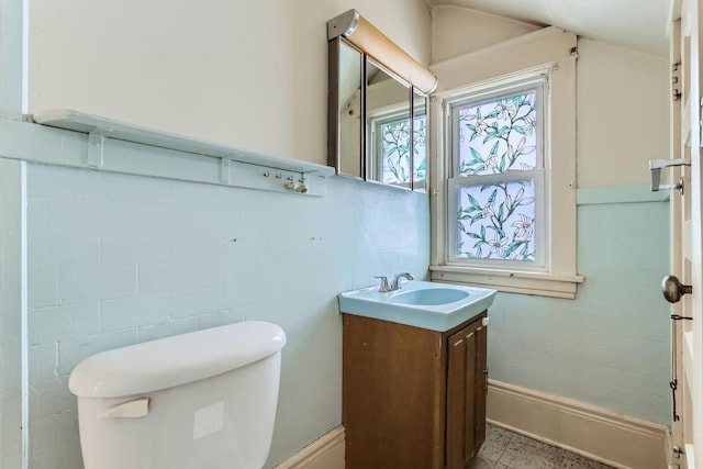 bathroom with vanity, vaulted ceiling, tile walls, and toilet