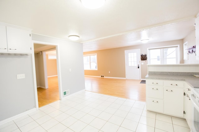 kitchen featuring light tile patterned floors, stove, and white cabinetry