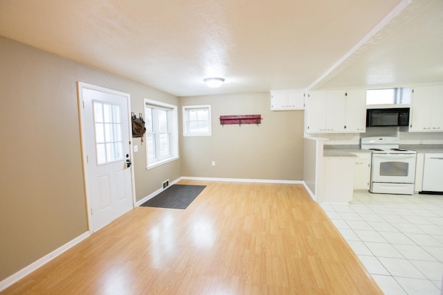 kitchen with white cabinets, a textured ceiling, white appliances, and light hardwood / wood-style flooring