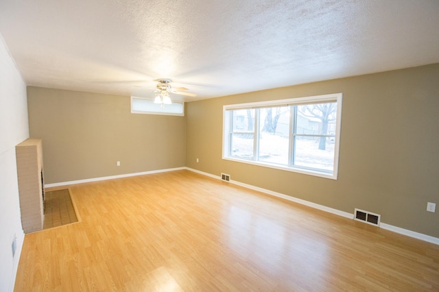 empty room with ceiling fan, wood-type flooring, and a textured ceiling