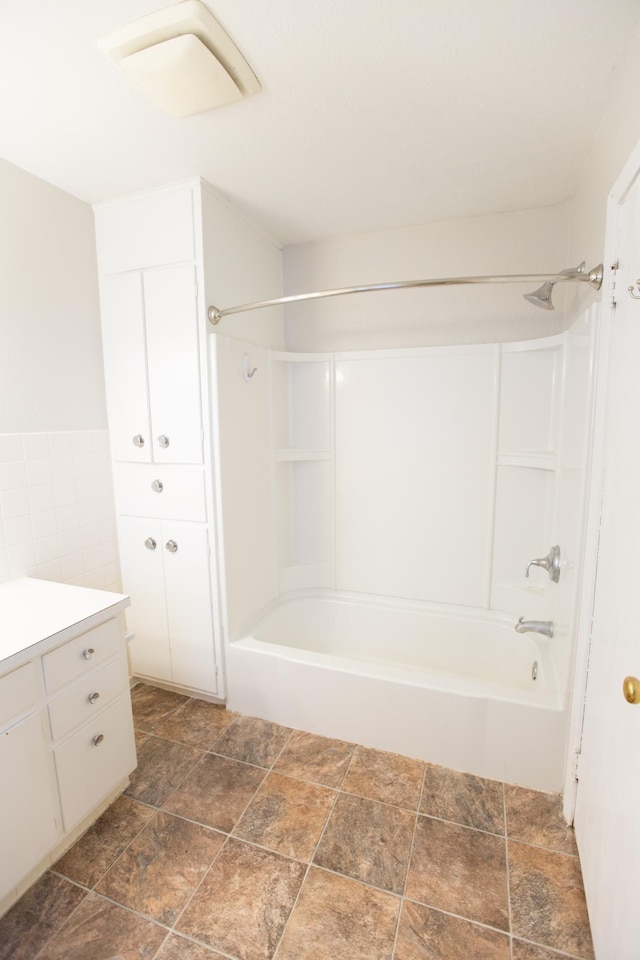 bathroom with shower / tub combination, vanity, and tile walls