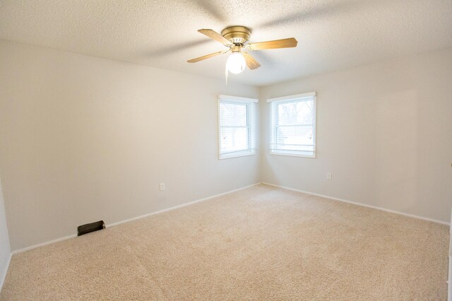 empty room with carpet flooring, ceiling fan, and a textured ceiling