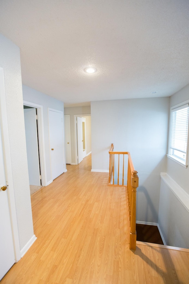 hallway with light hardwood / wood-style floors and a textured ceiling