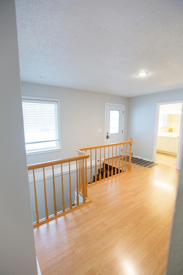 hall with a textured ceiling and light hardwood / wood-style floors